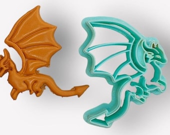 Könnte beinhalten: Zwei Drachen-Ausstecher, einer ist orange und der andere türkisblau. Beide sind mit Flügeln und einem Schwanz verziert.