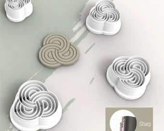 May include: Five white plastic cookie cutters shaped like a flower with a swirl design. The cutters are on a light gray surface. One cutter is gray and is on a white surface. The image also shows a close-up of the cutter's edge, which is sharp. The text "Sharp" is visible in the image.