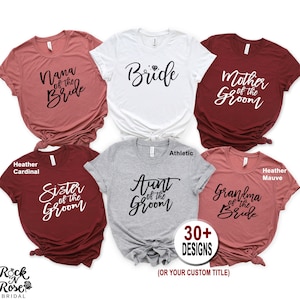 May include: Six different t-shirt designs for a wedding party. The shirts are in various colors, including heather cardinal, athletic grey, and heather mauve. The text on the shirts includes "Bride", "Mother of the Groom", "Sister of the Groom", "Aunt of the Groom", "Grandma of the Bride", and "Nana of the Bride".