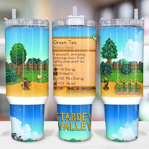 Könnte beinhalten: Ein Edelstahlbecher mit einem Stardew Valley-Design. Der Becher zeigt einen blauen Himmel mit weißen Wolken, grüne Bäume und eine Figur, die auf einem Pferd reitet. Der Text "Green Tea Artisan Goods" ist auf dem Becher sichtbar, sowie der Text "Stardew Valley".
