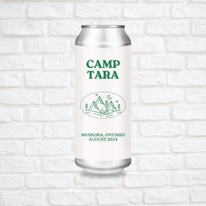 Peut inclure: Une canette argentée avec une étiquette blanche sur laquelle est inscrit "CAMP TARA" en lettres vertes. L'étiquette présente également un dessin au trait vert de montagnes, une tente, une lune et des étoiles. Le texte "MUSKOKA, ONTARIO AOÛT 2024" figure également sur l'étiquette.
