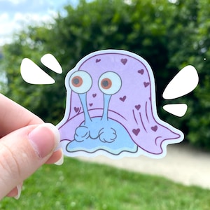 May include: A blue snail wearing a pink blanket with hearts printed on it. The snail has large, round eyes and a small mouth.
