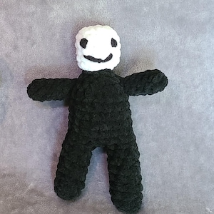 Puede incluir: Un juguete de peluche negro tejido a crochet con una cabeza blanca tejida a crochet y una cara sonriente.
