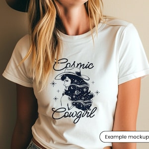 May include: White t-shirt with a black and white illustration of a woman wearing a cowboy hat with stars and planets in her hair. The text "Cosmic Cowgirl" is printed below the illustration.