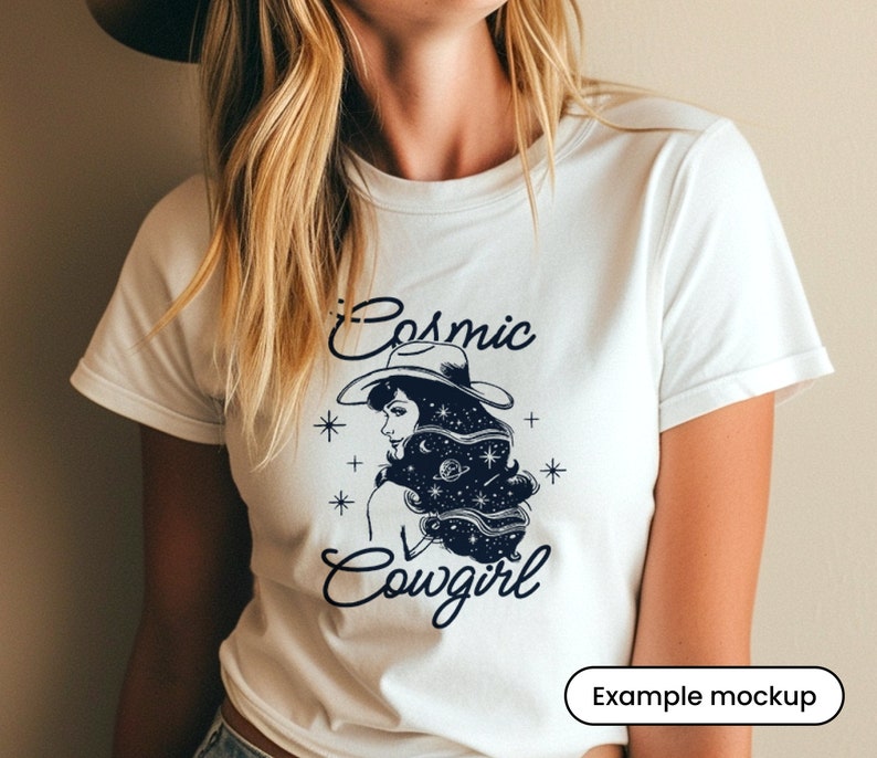 May include: White t-shirt with a black and white illustration of a woman wearing a cowboy hat with stars and planets in her hair. The text "Cosmic Cowgirl" is printed below the illustration.