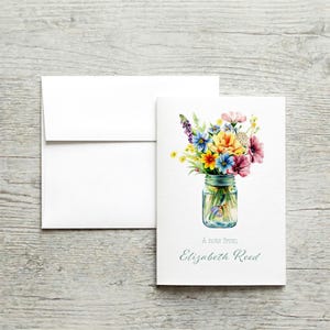 May include: A white greeting card with a watercolor illustration of a colorful flower bouquet in a mason jar. The card includes a white envelope and the text "A note from Elizabeth Reed."