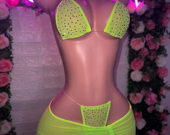 May include: A lime green mesh bikini set with crystal embellishments. The top is a triangle style and the bottom is a skirt with a high waist.