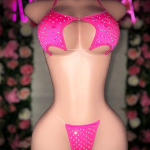 Op de afbeelding: Roze lingerie set met strass. De top heeft een uitsnijding en de onderkant is een string.