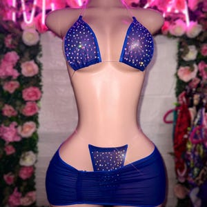 May include: A blue mesh bikini set with crystal embellishments. The top is a triangle style with thin straps and the bottom is a high-waisted, ruched skirt.