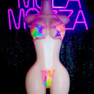 May include: A rainbow tie-dye bikini with rhinestones. The top has a keyhole cutout and the bottom is a thong style.