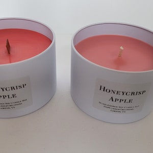 May include: Two white candle jars with pink wax and wooden wicks. The labels read "Honeycrisp Apple" and are handmade soy candles.