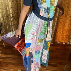May include: A long patchwork skirt made from various fabrics in shades of blue, green, red, yellow, and pink. The skirt has a drawstring waist and a variety of patterns, including plaid, polka dots, and floral prints.
