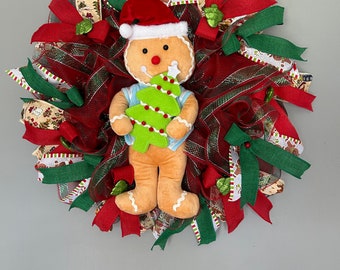 Un bonhomme en pain d'épice tenant une décoration pour sapin de Noël