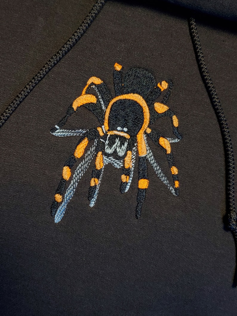 May include: Black hoodie with an embroidered yellow and black tarantula spider on the front.