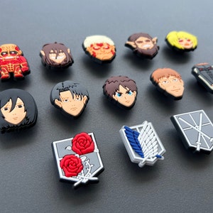 May include: A collection of colorful shoe charms featuring characters and symbols from the anime series Attack on Titan. The charms include character faces and the Survey Corps emblem, in various colors and designs.