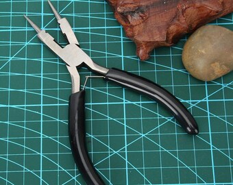 May include: Black and silver jewelry pliers with black rubber handles. The pliers are on a green cutting mat.