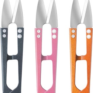 May include: Three pairs of small scissors with different colored handles: gray, pink, and orange. The scissors have a pointed tip and are designed for crafts and sewing.