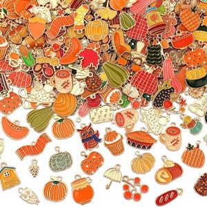 May include: A collection of fall-themed charms in various shapes and colors. The charms include pumpkins, gourds, leaves, mugs, and other autumn-related designs. The charms are made of metal and have a gold finish with enamel details.