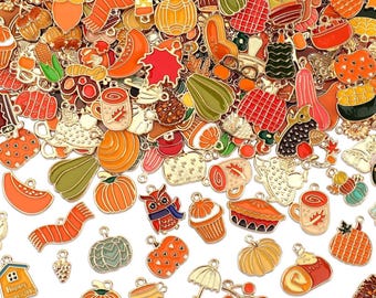 Könnte beinhalten: Eine Sammlung von Charms zum Thema Herbst in verschiedenen Formen und Farben. Die Charms umfassen Kürbisse, Kürbisse, Blätter, Tassen und andere herbstbezogene Designs. Die Charms sind aus Metall mit Emaille-Details.