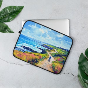 May include: Laptop sleeve featuring a vibrant landscape painting of a coastal path with a cyclist, ocean, and sky. The artwork uses a palette of blues, greens, yellows, and pinks. The sleeve has a black zipper and trim.