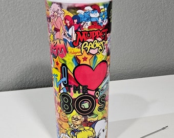 Puede incluir: Un vaso de acero inoxidable con un diseño colorido que presenta personajes de dibujos animados de los 80 y el texto "I Love The 80s". El vaso viene con una pajita de acero inoxidable y un cepillo de limpieza.