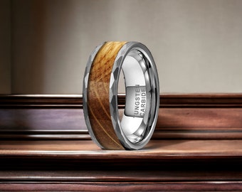 May include: A tungsten carbide ring with a wood inlay and a brushed finish. The ring is engraved with the words "Tungsten Carbide".