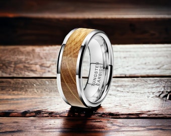 May include: A silver tungsten carbide ring with a brown wood inlay. The ring is engraved with the words "TUNGSTEN CARBIDE".