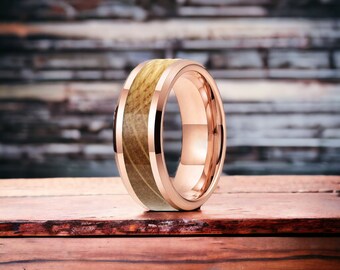 May include: A rose gold tungsten carbide ring with a wood inlay. The ring has a beveled edge and a polished finish.