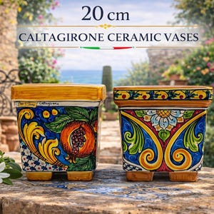 Può includere: Due vasi in ceramica di Caltagirone, ciascuno di 20 cm di altezza, con disegni dipinti a mano. I vasi quadrati presentano un bordo e una base gialli, con intricati motivi floreali e fruttati blu, gialli e rossi. Il testo "CALTAGIRONE CERAMIC VASES" è visualizzato sopra.