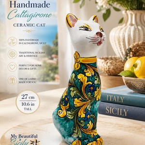 May include: A ceramic cat figurine standing 10.6 inches tall, featuring a white head with painted facial details and a body decorated with intricate yellow and blue floral patterns on a teal background, finished with a yellow collar.