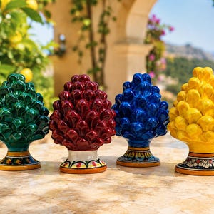 Peut inclure: Quatre sculptures en céramique en forme de pomme de pin alignées. Chaque pièce présente une finition brillante en vert, rouge foncé, bleu ou jaune. La base de chaque sculpture est ornée de motifs floraux peints à la main aux couleurs variées.