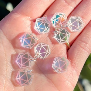 May include: A collection of iridescent clear plastic dice charms with silver jump rings. The dice are shaped like a twenty-sided die.