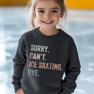 May include: A dark gray sweatshirt with the text "SORRY. CAN'T. ICE SKATING. BYE." in a vintage style font. The text is in shades of blue, green, and pink.