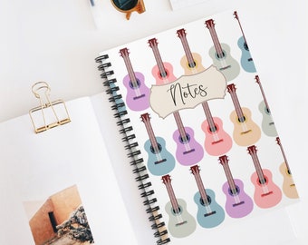 May include: A white spiral bound notebook with a colorful ukulele pattern. The notebook has the word "Notes" written on the front.