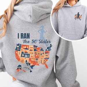 May include: A gray hooded sweatshirt with the text "I RAN The 50 States" and a colorful map of the United States. The map is filled with various icons. A silhouette of a runner is on the back and front of the sweatshirt.