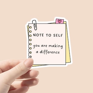 May include: A yellow and white notepad with a pink heart sticker and a paperclip. The notepad says "Note to self you are making a difference".