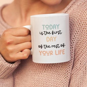 May include: White ceramic mug with the text "TODAY is the first DAY of the rest of YOUR LIFE" in colorful lettering.