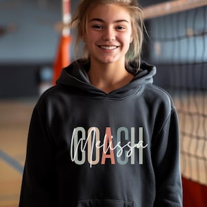 May include: A black hooded sweatshirt with the text "COACH Melissa" in colorful letters.