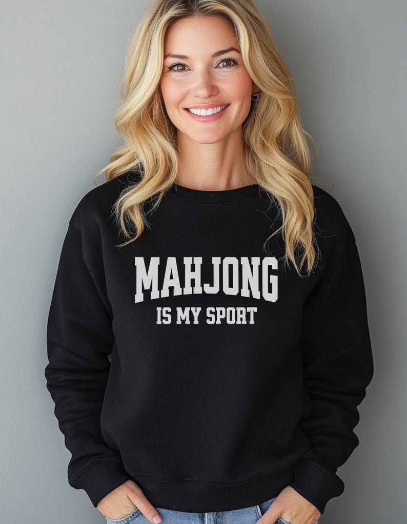 May include: Black crew neck sweatshirt featuring the white text "MAHJONG IS MY SPORT". The sweatshirt is made of a soft material. The design is a casual, game-themed apparel item, suitable for everyday wear.