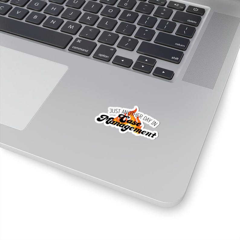 May include: A white sticker with a black and orange flame design. The text "Just another day in Case Management" is written in black on the sticker.