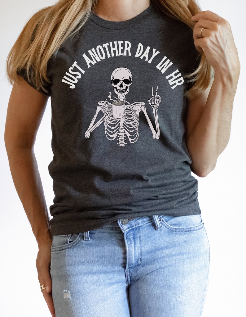 May include: A dark gray t-shirt with a skeleton holding a coffee cup and the text "Just another day in HR".