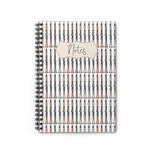 May include: A white spiral bound notebook with a colorful clarinet pattern and the word "Notes" in a decorative banner.