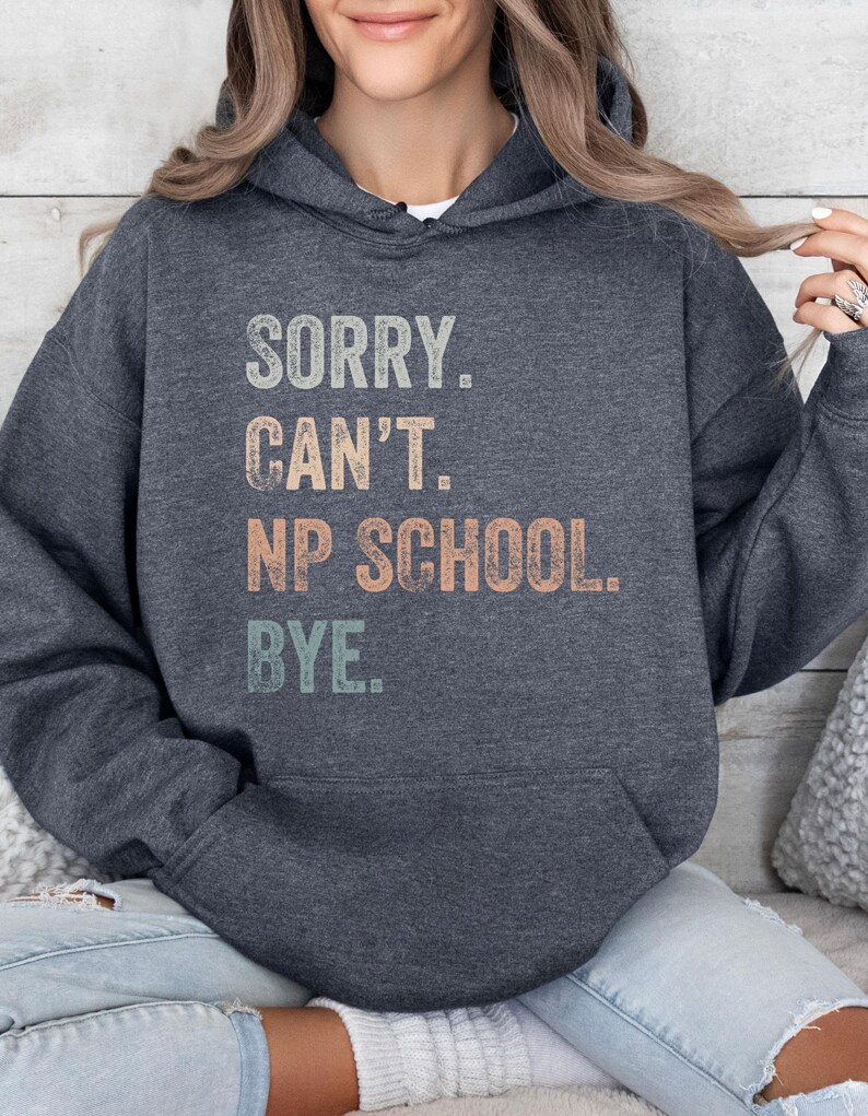 May include: A dark gray hooded sweatshirt with the text "SORRY. CAN'T. NP SCHOOL. BYE." printed in a vintage style with colorful lettering.