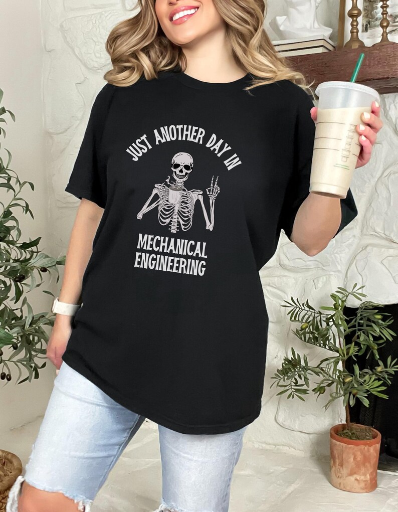 May include: Black t-shirt with a skeleton holding a coffee cup and the text "Just another day in mechanical engineering".