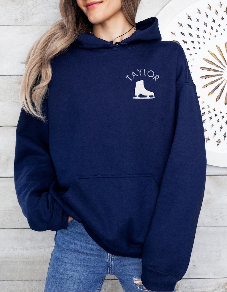 May include: A navy blue hoodie with a white ice skate graphic and the word 'TAYLOR' printed on the front.