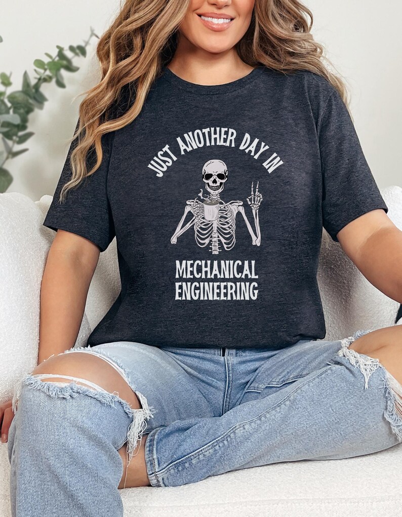 May include: A dark gray t-shirt with a white skeleton graphic and the text "Just another day in mechanical engineering".