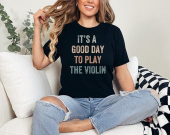May include: A black t-shirt with a vintage-style graphic that reads "It's a good day to play the violin".