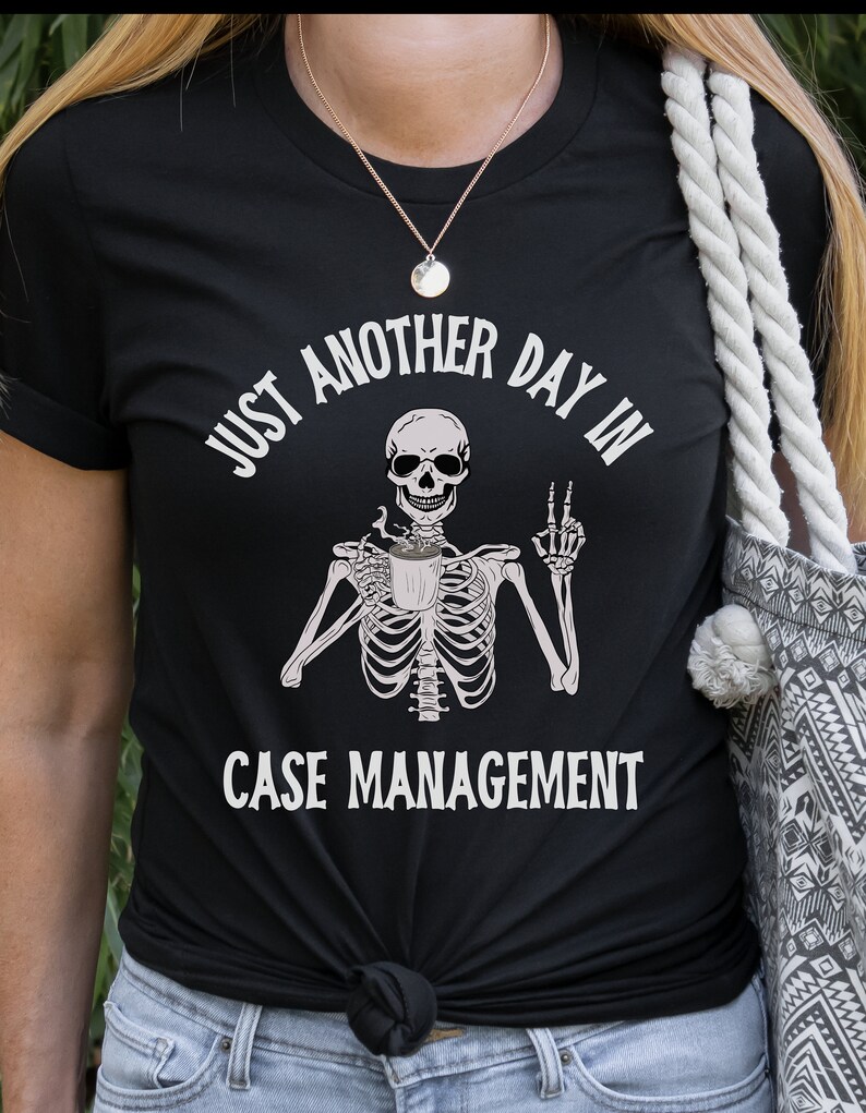 May include: Black t-shirt with a white skeleton holding a coffee cup and the text "Just another day in case management".