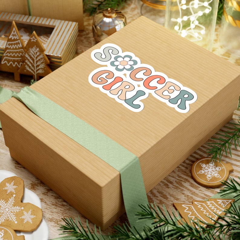 May include: A brown gift box with a green ribbon and a sticker that says "Soccer Girl" in colorful letters with a flower design.