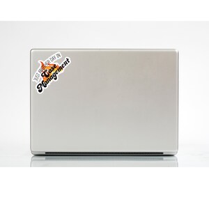 May include: A silver laptop with a sticker that says "Just another day in Case Management". The sticker has a flame design with orange and yellow colors.